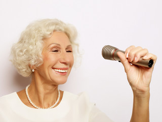 lifestyle and people concept: Portrait of charming modern grandmother holds up the microphone