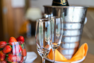 Wineglass and a bottle of chilled champagne are in an ice bucket for welcoming guests in hotel