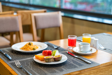 Fresh romantic breakfast table next to morning briliant light window, with spaghetti, fruit, juice
