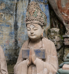 Statue of disciple or follower in front of giant Buddha at Dazu Rock Carvings at Mount Baoding or Baodingshan in Dazu, Chongqing, China. UNESCO World Heritage Site.