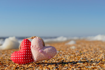 Image of a soft toy in the shape of a heart on the beach.