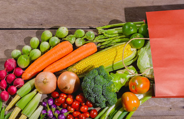 Backgroud of fresh food tasty and healthy many vegetables come out of paper shopping bag on the wooden table