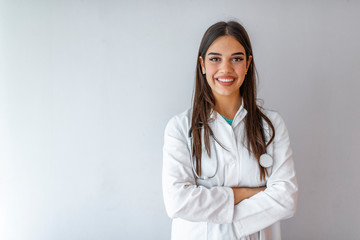 Confident doctor standing arms crossed. Confident smilling young woman doctor. Intern Doctor Young pretty woman in white clothes with a phonendoscope and medical mask posing and smiling.