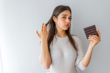 Closeup Acne Problem Face Woman Eating Chocolate bar. Young woman with acne problem eating...