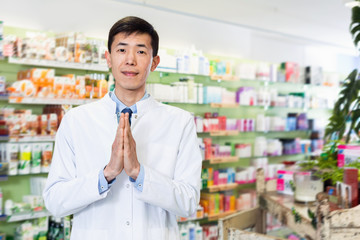 Portrait of chinese man pharmacist who is standing on his work place in apothecary.