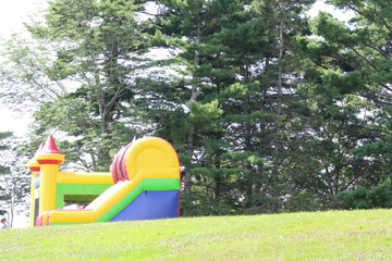 A colorful blown up bouncy castle on a grass field