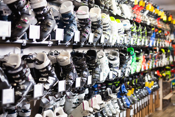 Different models of boots for alpine skiing on shelves in shop