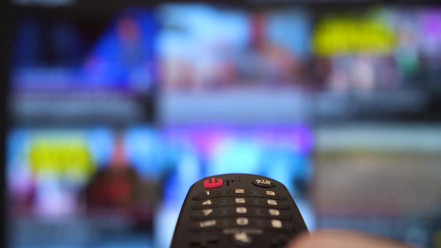 Smart tv and hand pressing remote control. TV screen Channel surfing. focused on the hand and remote control and turn off smart tv