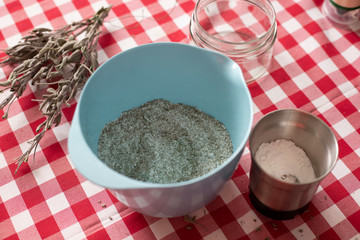 Blue bowl containing aromatics herbs - like dried sage and rosemary - mixed with sea salt using a blender, an homemade seasoning for everyday cooking.