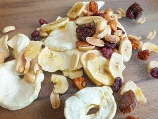 Detail shot of dehydrated fruit of apple, banana, raisins, rhubarb and nuts on a glass board.