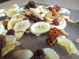 Detail shot of dehydrated fruit of apple, banana, raisins, rhubarb and nuts on a glass board.