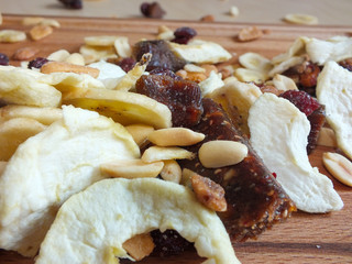 Detail shot of dehydrated fruit from apple, banana, raisins, rhubarb and nuts on a wooden board.