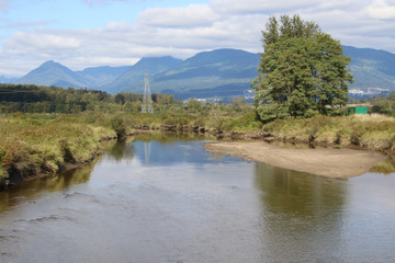 Fototapeta premium A view of a low river with a power line tower in the background
