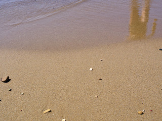 Fototapeta na wymiar Human figure reflection on sandy beach surface.
