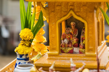 Miniature guardian spirit house. Small buddhist temple shrine, colorful flower garlands. San phra...