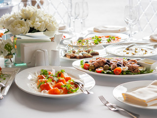 Table served for banquet.Plate with salmon fish. Tasty appetizer. Peony flowers in vases. Pastel colored decorations.