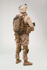 Soldier in US marines uniform with rifle on light grey background, studio shot
