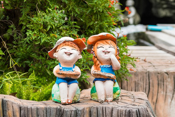 Happy boy and girl dolls made from baked clay decorative in a garden.