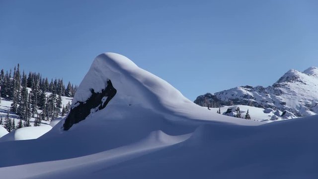 4K Timelapse showing the sun setting in snowy backcountry deep within the mountains. A big shadow falls over the cold winter landscapes as it turns night.