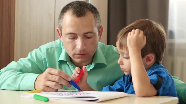 Happy family. Father and child. Dad spends time with his son imagining and painting a picture with colored markers.