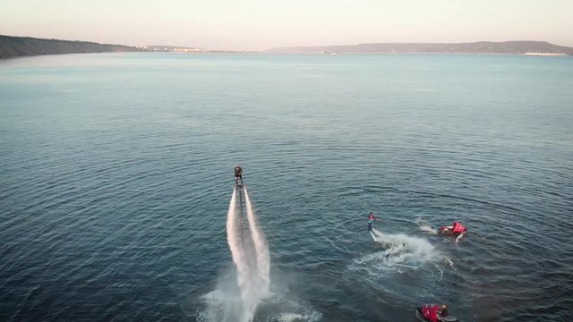 Sportive people flying over water with jet packs