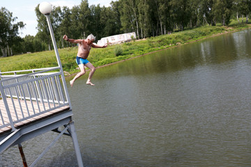 Man jumping from bridge into lake