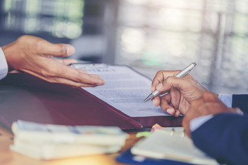Crop image of businessman puts signature on contract at business meeting and passing money after negotiations with business partners