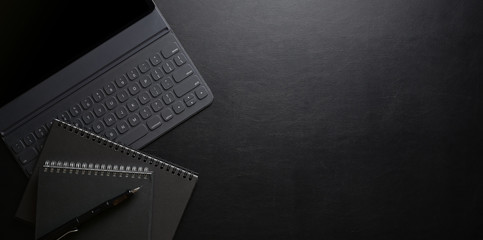 Dark stylish workplace with laptop computer and office supplies on black lather desk background