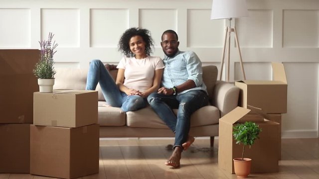 Parents resting on couch looking to kids running holding boxes