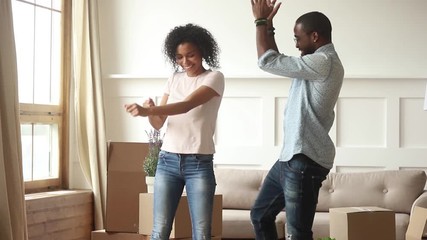 Black couple celebrating moving at new home dancing feels happy