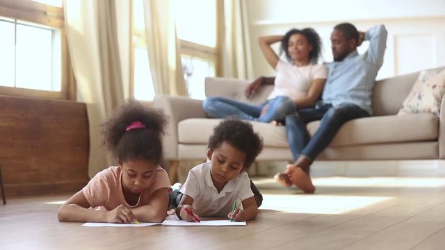 While parents resting on couch kids drawing on warm floor