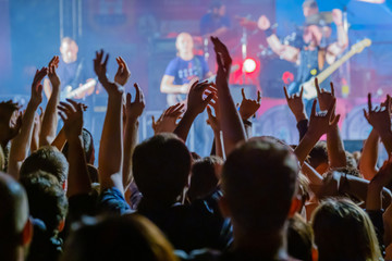 Fans cheering musicians on stage at live rock music concert
