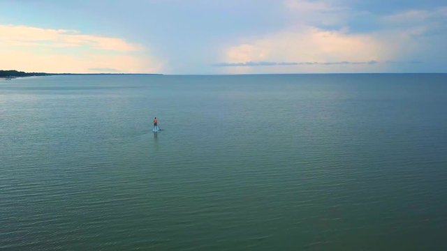 A dramatic drone shot of a lone kayaker slowly driffting into a colorful sunset
