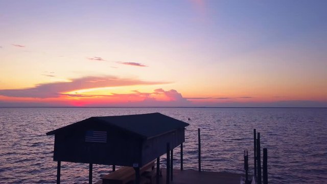 A dramatic drone shot of a lone kayaker slowly driffting into a colorful sunset