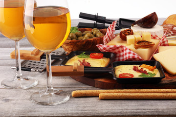 Delicious traditional Swiss melted raclette cheese on diced boiled or baked potato and baguette served in individual skillets with salami..