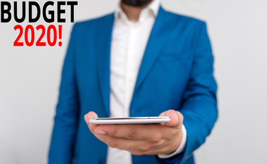 Word writing text Budget 2020. Business photo showcasing estimate of income and expenditure for next or current year Business concept with man holding mobile phone with touch screen