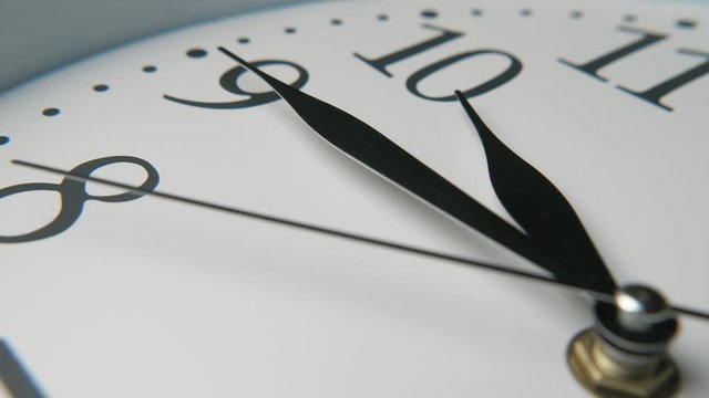 Ancient-looking white clock face put askew pointing at fifteen minutes to ten  