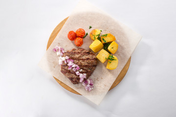Grilled Beef Steak with Potato, red onion and tomato on wooden board isolated on white background