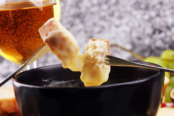 Gourmet Swiss fondue dinner on a winter evening with assorted cheeses on a board alongside a heated...