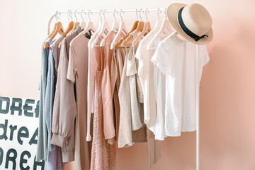 Rack with clothes near color wall in room
