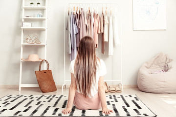 Young woman choosing clothes in her dressing room, back view