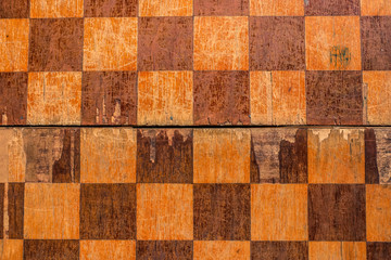 Old shabby chessboard texture top view. Chekered wooden background.
