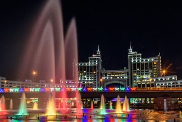 Fototapeta na wymiar Nur-Sultan, Kazakhstan, August 2019, Fountains with lighting on the background of tall buildings in the center of the capital of Kazakhstan.
