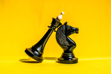 Colorful concept with black chess king and chess knight. Bright yellow background.