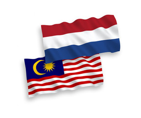 National vector fabric wave flags of Malaysia and Netherlands isolated on white background. 1 to 2 proportion.