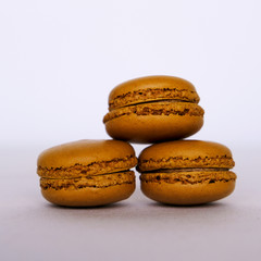Stack of fresh delicious caramel macarons on beige background, close up
