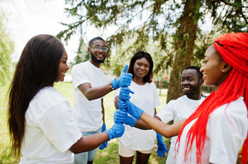 Group of happy african volunteers put hands in hands in park. Africa volunteering, charity, people and ecology concept.