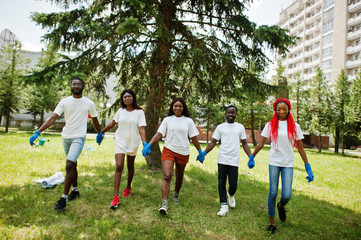 Obraz na płótnie Canvas Group of happy african volunteers hold hands together in park. Africa volunteering, charity, people and ecology concept.