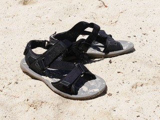 Pair of adult black sandals in the sand