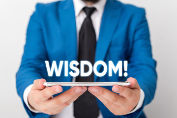 Handwriting text writing Wisdom. Conceptual photo quality having experience knowledge and good judgement something Businessman in blue suite with a tie holds lap top in hands